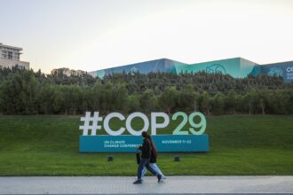 Citizens walks near a sign for COP29 near the Baku Olympic Stadium, the venue of the COP29 United Nations Climate Change Conference on October 23, 2024 in Baku, Azerbaijan.