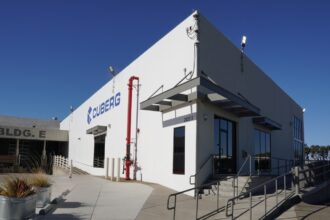 Cuberg's old manufacturing facility stands against a blue sky.