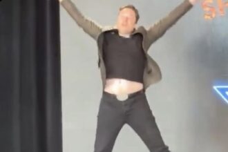 Elon Musk jumping up and making an X with his body