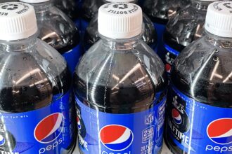 Three plastic bottles of Pepsi on a store shelf, side by side.