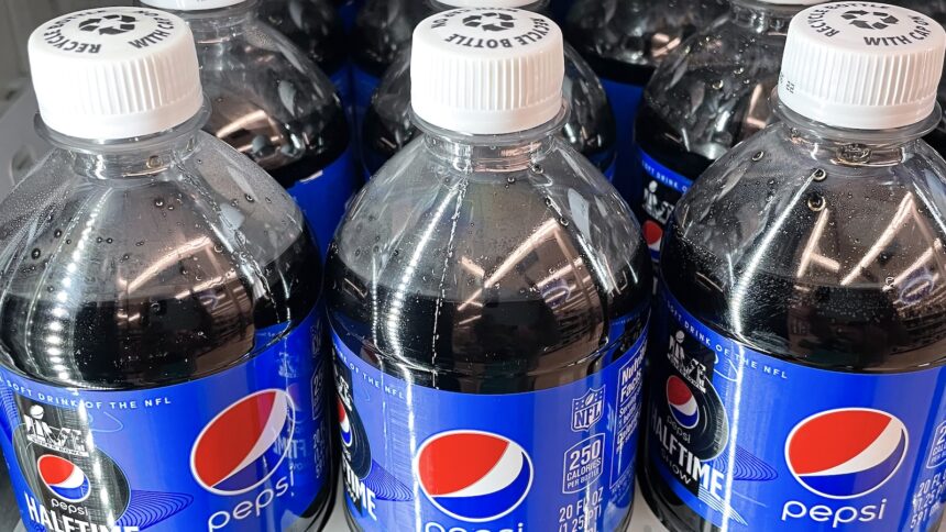 Three plastic bottles of Pepsi on a store shelf, side by side.