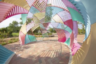 the interior of a colorful metal outdoor installation shaped like a dome with geometric facets