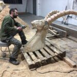 artist Quentin Garel working on a wooden sculpture of an ibex in his studio