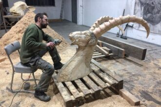 artist Quentin Garel working on a wooden sculpture of an ibex in his studio