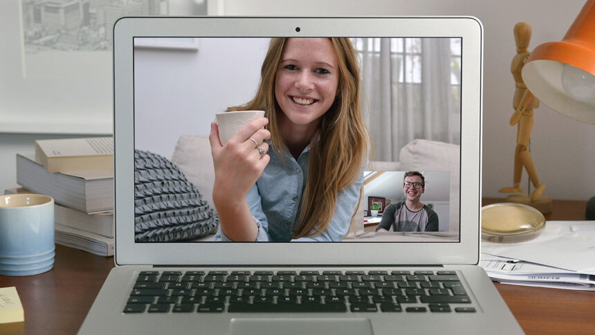 A woman on a computer screen smiles while she looks at a smaller square of a man, who is also smiling.