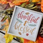 An image with sign that says Thankful & Blessed placed on a pumpkin and autumn plants.