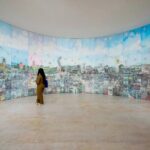 a woman stands in front of a round installation with various imagery