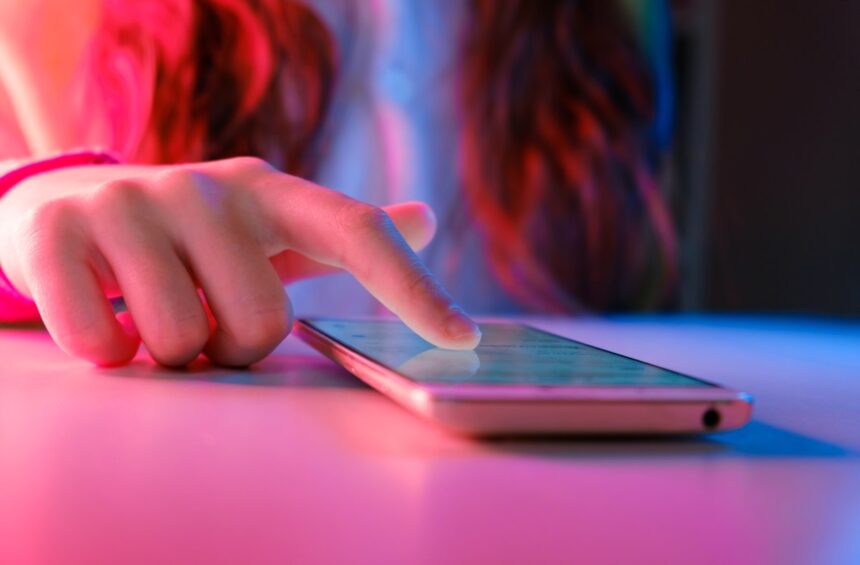 person touching a smartphone laying on a table.