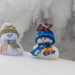 Two tiny snowmen standing in the snow of winter.