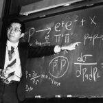 Physicist Samuel Ting points at equations on a blackboard that describe the subatomic particle J/psi.