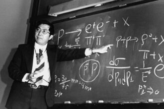 Physicist Samuel Ting points at equations on a blackboard that describe the subatomic particle J/psi.