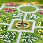 detail of a lush aerial landscape of a symmetrical garden with flowers and walkways stitched with thread inside an embroidery hoop