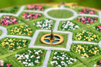 detail of a lush aerial landscape of a symmetrical garden with flowers and walkways stitched with thread inside an embroidery hoop