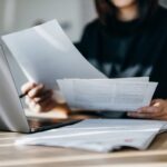 Cropped shot of young Asian woman handling personal banking and finance with laptop at home