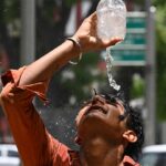 A boy in India pours water over his head.