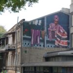 a large mural on the side of a building of a woman hanging out her laundry