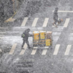 people cross a street during a major winter storm in New York City