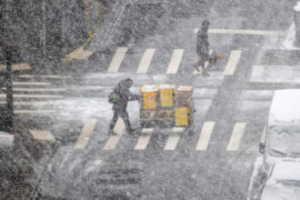 people cross a street during a major winter storm in New York City