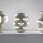 three ceramic vessels with shiny enamel coating that is intersected with curves of white neon lights