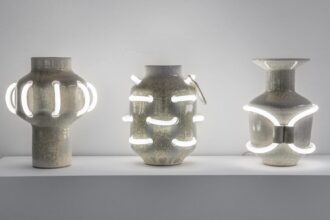 three ceramic vessels with shiny enamel coating that is intersected with curves of white neon lights