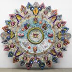 an abstract glass sculpture in the form of an Aztec calendar with numerous mixed-media details and patterns