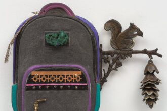 a backpack sculpture with a spigot on the lower left and a branch with a squirrel and a pinecone emerging from the top right