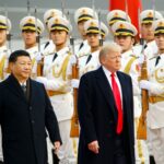 Donald Trump and Xi Jinping walk together in front of a group of uniformed Chinese soldiers.