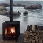 a painting of a wood stove with a fire inside in front of a pond with stones in it