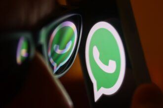 WhatsApp logo reflected on sunglasses and displayed on a phone screen.