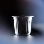 An aluminum single-serve coffee pod against a black and blue background