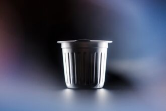 An aluminum single-serve coffee pod against a black and blue background