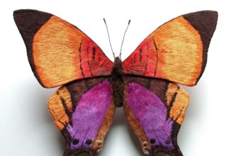 a strikingly realistic sculpture of a yellow and purple butterfly made from embroidery thread and wire