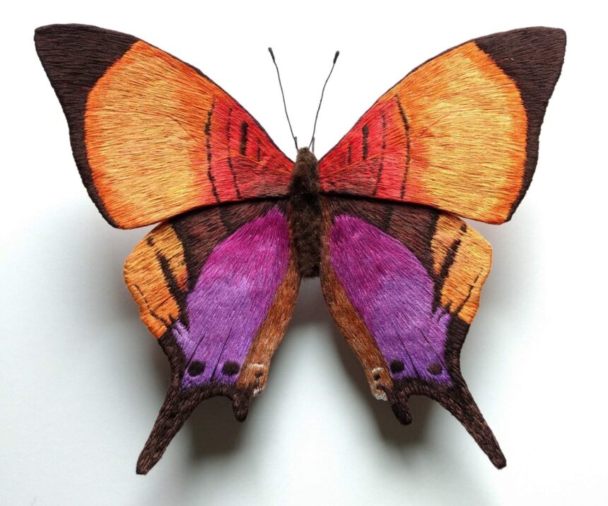 a strikingly realistic sculpture of a yellow and purple butterfly made from embroidery thread and wire