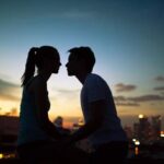 A couple about to kiss at sunset with a city in the background.