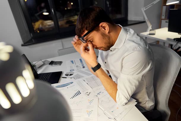 A tired looking man working late at night in an office.