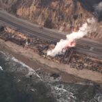 An aerial view of a wildfire burning home along the beach