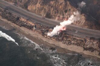 An aerial view of a wildfire burning home along the beach