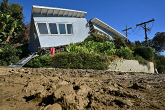 A wrecked house is in the background, while mud fills the foreground