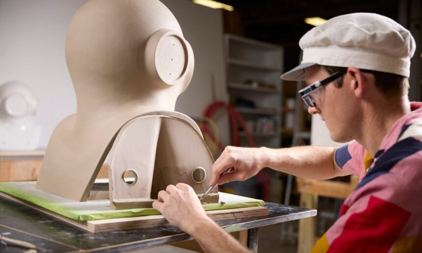 an artist works on a large almost figurative sculpture on a table