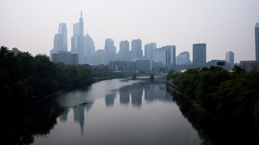 A gray skyline looms over a river in a sky filled with white smoke