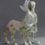 a glass and ceramic sculpture of a woman standing with a deer