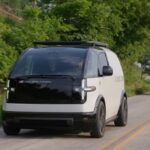 Two Canoo EVs drive on a road in Bentonville, Arkansas.