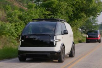 Two Canoo EVs drive on a road in Bentonville, Arkansas.