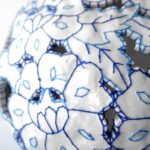 a detail of a white porcelain vessel embroidered with blue cotton thread