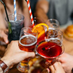 People raise their glasses of alcoholic drinks to toast each other.