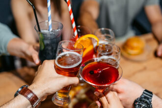 People raise their glasses of alcoholic drinks to toast each other.