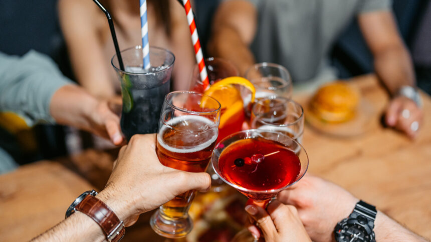 People raise their glasses of alcoholic drinks to toast each other.