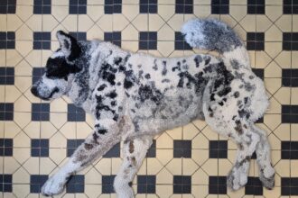 a realistic relief textile work of a dog lounging on a tiled floor, made via rug hooking