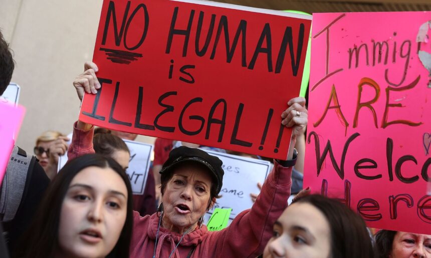 A woman holds up a sign reading "no human is illegal" at a 2017 protest in Miami.