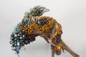 a botanical sculpture of bird, made from glass, wood, and ceramics